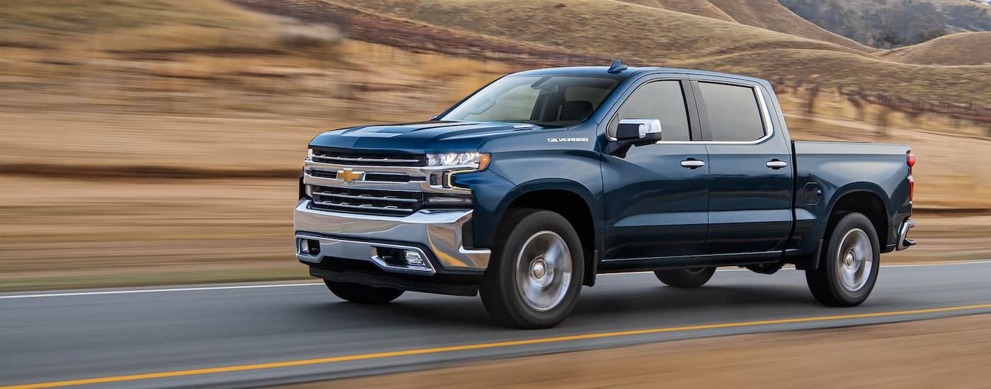 Blue 2021 Chevy Silverado 1500 driving down an open road