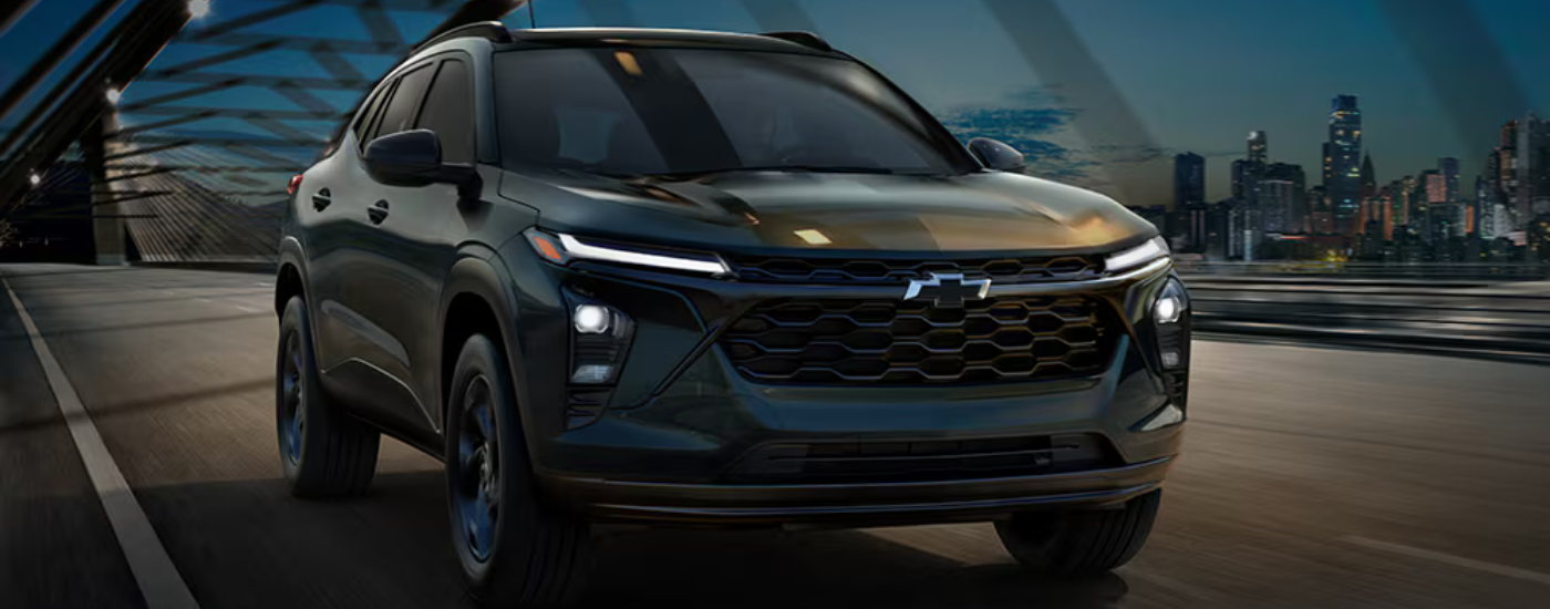 Black 2026 Chevy Trax driving over a bridge at night