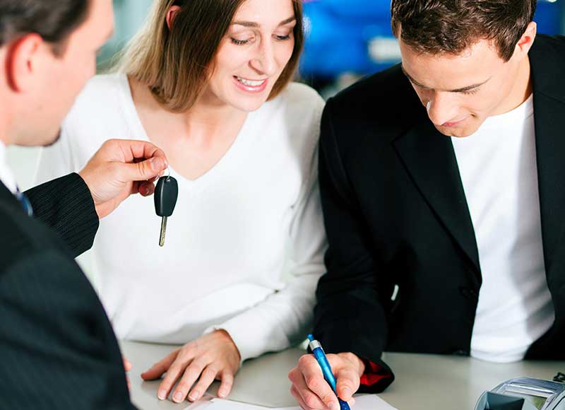 Man signing car deal with his wife at his side